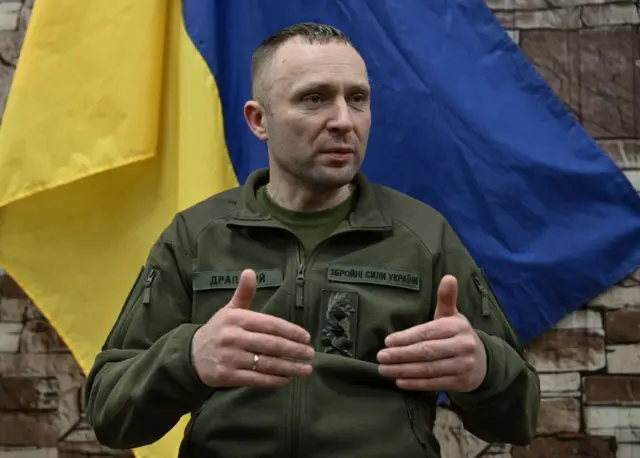 Драпатий на тлі українського прапора на стіні