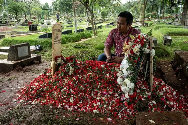 Seorang teman berdoa di makam Affan Kurniawan yang dipenuhi bunga di Pemakaman Umum Karet Bivak, Jakarta pada 29 Agustus 2025.