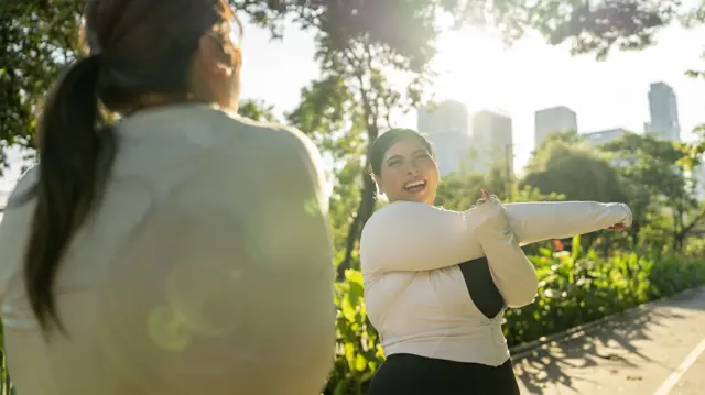 Mujer sonriendo mientras estira los brazos