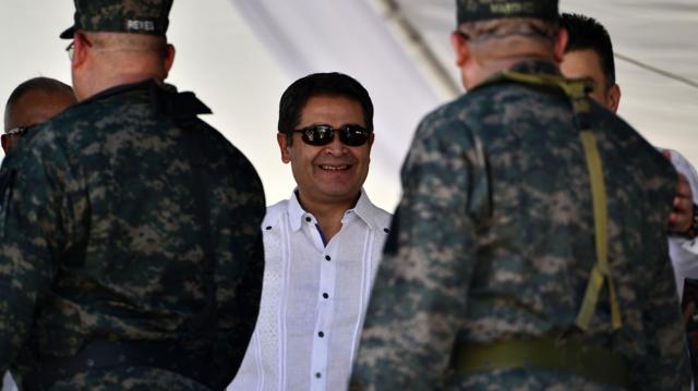 Juan Orlando Hernández sonríe rodeado de militares siendo presidente de Honduras, en 2019