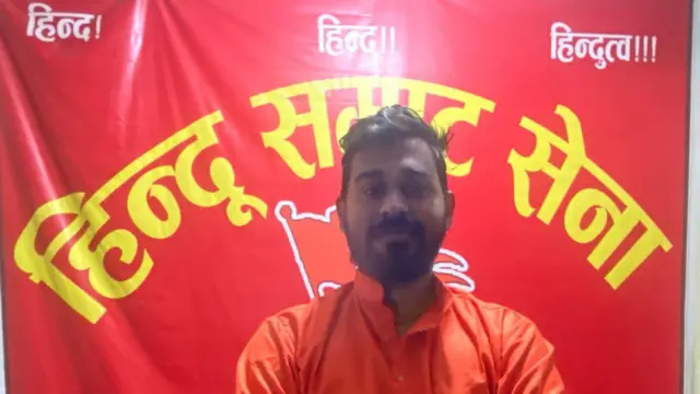 राजेश यादव हिन्दु सम्राट सेनाका नेता हुन्। सङ्गठनको ब्यानर अघि उभिएको अवस्थाको उनको तस्बिर। 