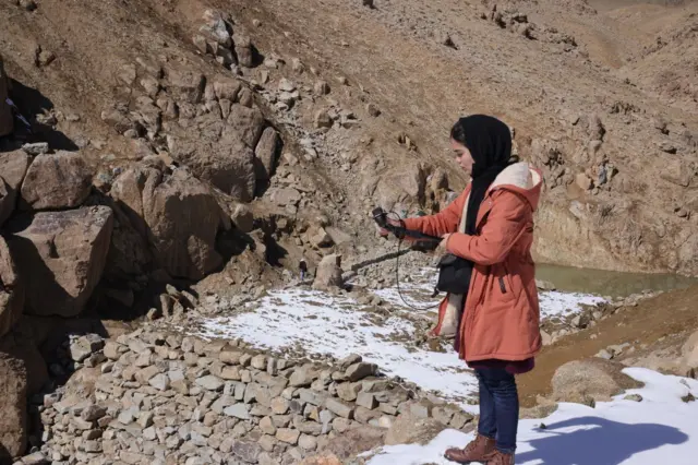 دختری در یک منطقه کوهستانی در حال تصویر برداری