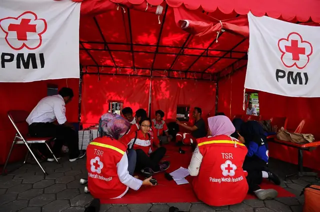 Personel Palang Merah Indonesia sedang memberikan bantuan kesehatan ke korban bencana. 