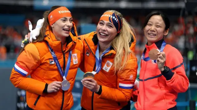 横に並んだ3人が首から下げたメダルに手をしながら笑顔を見せている