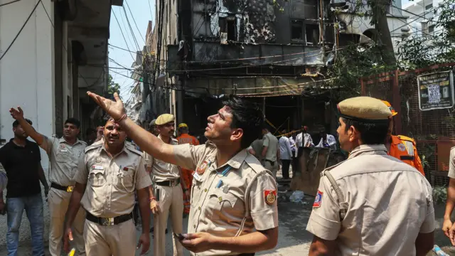 Firefighters stand at the site of a hotel fire in New Delhi , India