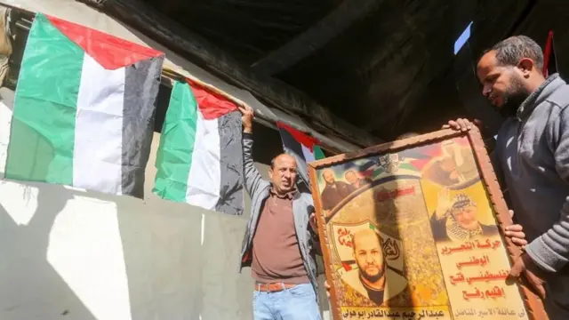 Homens palestinos com bandeiras palestinas e cartaz com fotopoker valendo dinheiro é crimeum homem 