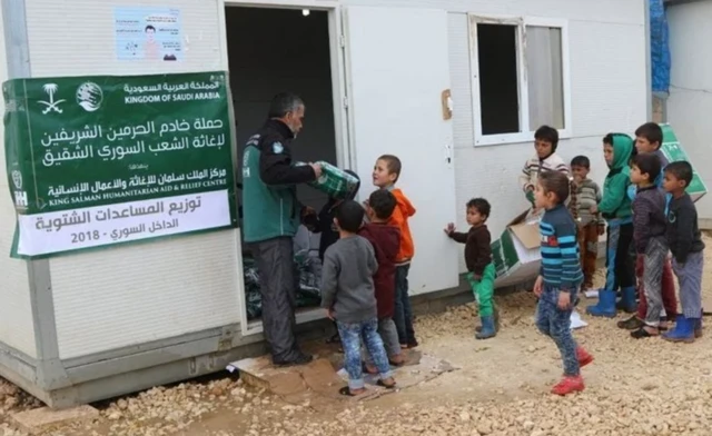 عامل تابع لمركز الملك سلمان للإغاثة والأعمال الإنسانية يوزع المساعدات الشتوية على الأطفال بداخل سوريا. (وكالة الأنباء السعودية)
