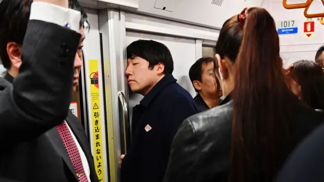 Homem dormindo encostado na porta do metrô