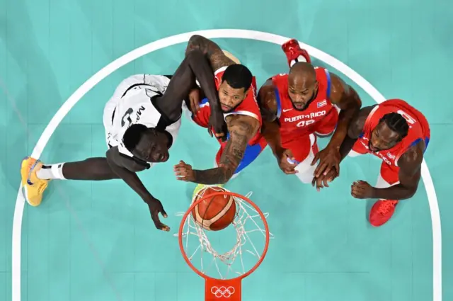 Umukinnyi wa Sudani y'Epfo ari kumwe n'abakinnyi batatu ba Puerto Rico bareba umupira uva mu nkangara