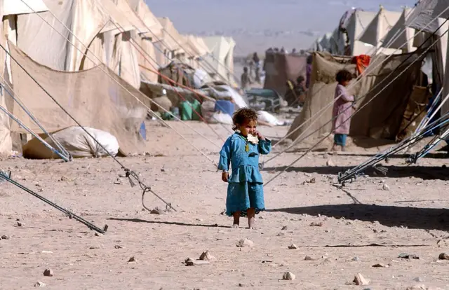 Une jeune fille afghane mange un morceau de pain dans le camp de réfugiés de Chaman, le 8 novembre 2001, à la frontière pakistanaise avec l'Afghanistan. 