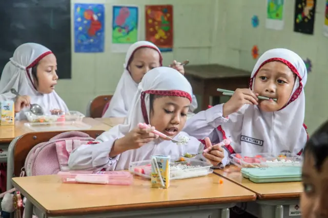 Para siswa menyantap makanan mereka sebagai bagian dari program MBG di sebuah sekolah di Surabaya, Jawa Timur, pada 13 Januari 2025.