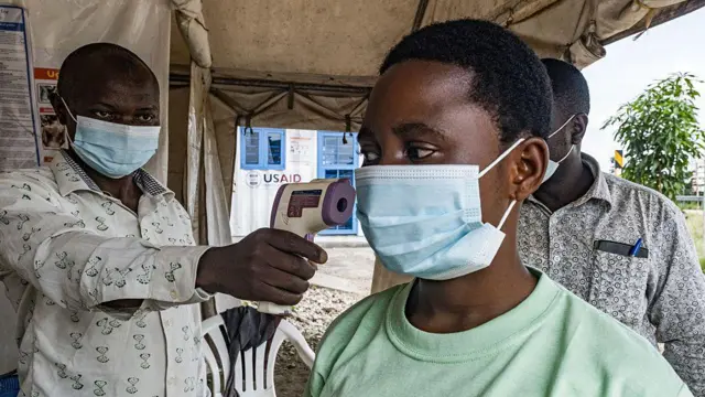 Pessoa tendo sua temperatura verificada com termômetro sem contato na fronteira entre Uganda e a República Democrática do Congo, no dia 18 de maio de 2026