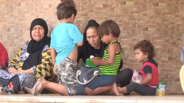 نساء مع أطفالهن يفترشن الأرض في المخيم