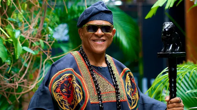 Farooq Oreagba ti ọpọ mọ si Mr Steeze ree pẹlu igo dudu loju, o n rẹrin musẹ, bẹẹ lo mu ọpa lọwọ