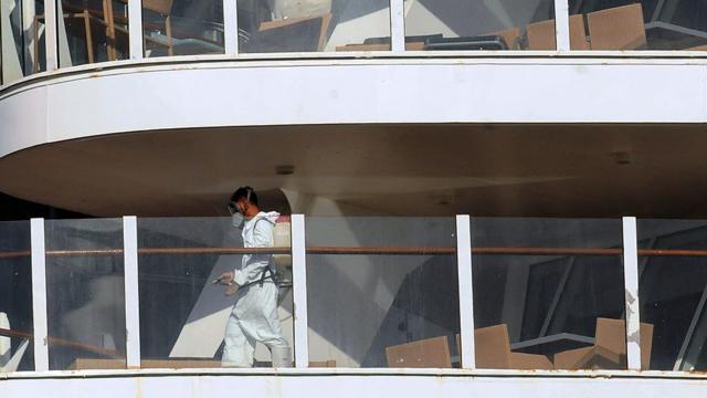 Imagem de pessoa paramentada e com máscara no deck de um navio