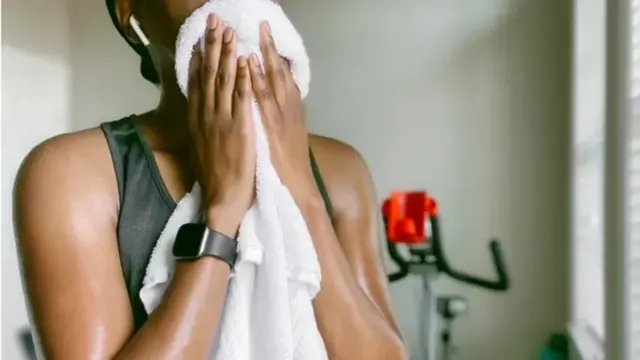Une femme s'essuyant avec une serviette après le sport.