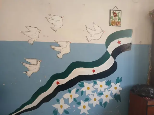 Şam'da bir devlet okulunun duvarında öğrencilerin boyaması görünüyor.