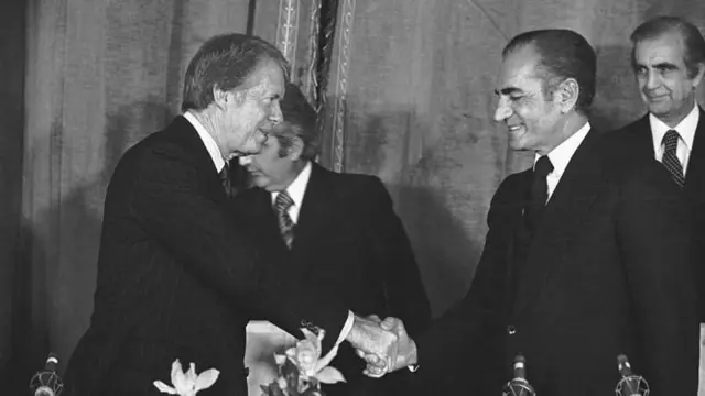 সাদা-কালো এই ছবিতে দেখা যাচ্ছে, ইরানের শাহ বংশের শেষ শাসক মোহাম্মদ রেজা পাহলভি (ডানে) পশ্চিমা বিশ্বের মিত্রদের সাথে হাসিমুখে হাত মেলাচ্ছেন