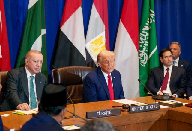 Trump ve Erdoğan yan yana oturuyor. Odada başka yetkililer de var. Trump öne eğilmiş şekilde konuşuyor. Erdoğan dinliyor.