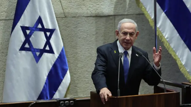 Binyamin Netanyahu bir kürsüde konuşma yapıyor, arkasında İsrail bayrağı var
