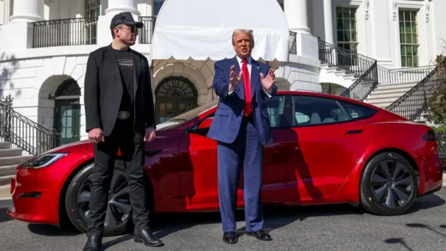Musk ve Trump, kırmızı bir Tesla aracının önünde poz veriyor 