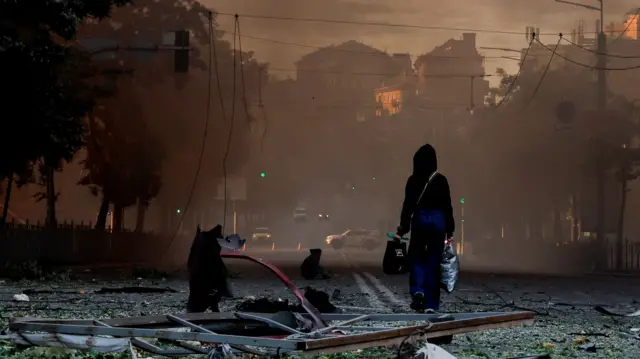 Osoba idzie ulicą zasypaną gruzem po nocnym rosyjskim ataku rakietowym i dronowym na Kijów, Ukraina, 24 maja 2026 r.