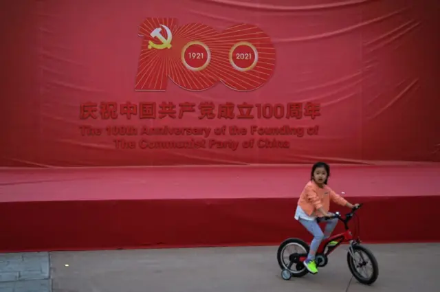 2021年5月10日,一名女孩骑着自行车,站在纪念中国共产党建党100周年的舞台旁。这张照片是在政府组织的媒体参观期间拍摄的。