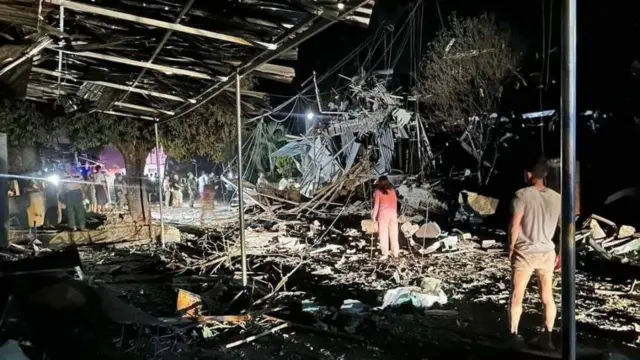 နမ့်ခမ်းမြို့ကို လေကြောင်းတိုက်ခိုက်မှုဖြစ်ပြီးတဲ့နောက် အပျက်အစီးတွေကြားထဲမှာ အမျိုးသား တစ်ဦးနဲ့ အမျိုးသမီးတစ်ဦးတို့ ရှာဖွေတာတွေလုပ်နေတာဖြစ်ပါတယ်။ ဓာတ်ပုံ ဘယ်ဘက်ခြမ်းမှာတော့ ဓာတ်မီးနဲ့ မီးထွန်းရှာဖွေသူတွေကို တွေ့ရပါတယ်။