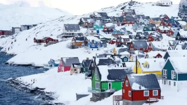 Гренландский пейзаж: заснеженный берег незамерзшего моря и разноцветные одноэтажные домики на нем