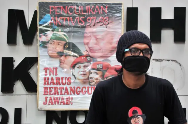 Foto yang diambil pada tanggal 20 Mei 2014 ini menunjukkan seorang pengunjuk rasa duduk di samping spanduk bertuliskan "Penculikan aktivis 1997-1998, TNI harus bertanggung jawab" selama unjuk rasa terhadap Prabowo Subianto di Jakarta.