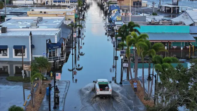 Un auto transita por una carretera inundada luego del huracán Helene