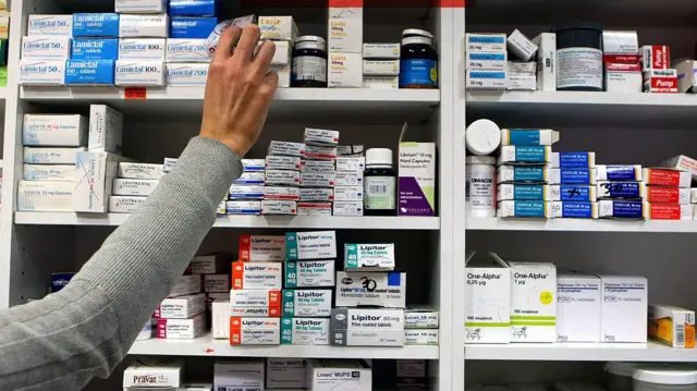 İlaç dolu raflara uzanan bir el. 