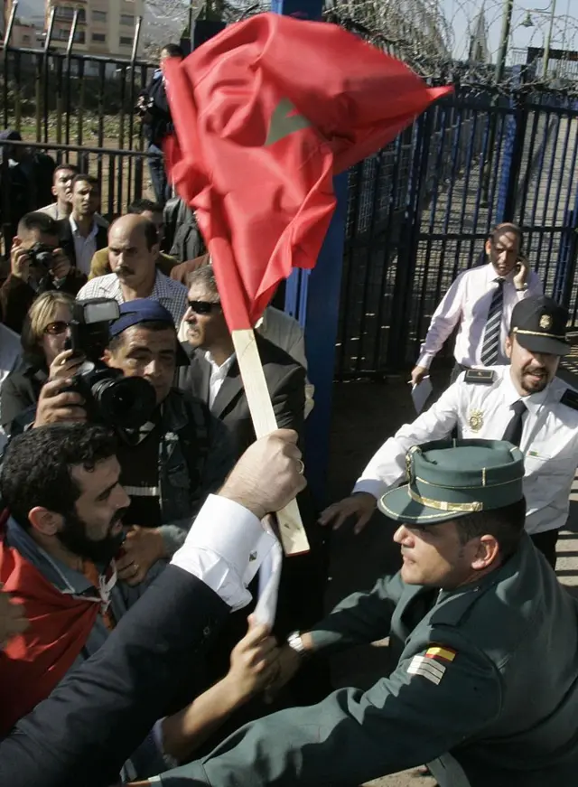 Marroquíes que se manifiestan (izquierda) se enfrentan a agentes de la Guardia Civil española mientras intentan entrar a la fuerza en territorio español —el 6 de noviembre de 2007— desde la localidad de Beni Nssar, en la frontera con el enclave español norteafricano de Melilla (derecha), en protesta por la visita de dos días de los reyes de España, Juan Carlos y Sofía, a los enclaves españoles de Melilla y Ceuta.