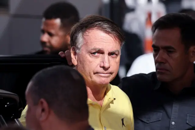 Jair Bolsonaro, de camisa amarela olhando para o lado 