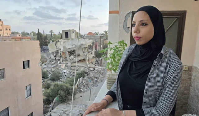 Yardım görevlisi Hanya Aljamal, yıkıntıların arasındaki apartmanının balkonunda poz veriyor.