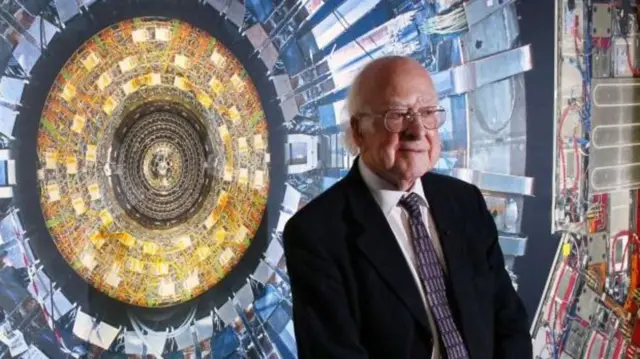 Na foto, Peter Higgs é um senhorbetspinpele clara, pouco cabelo, usando óculos, terno escuro sobre camisa branca e gravata. 