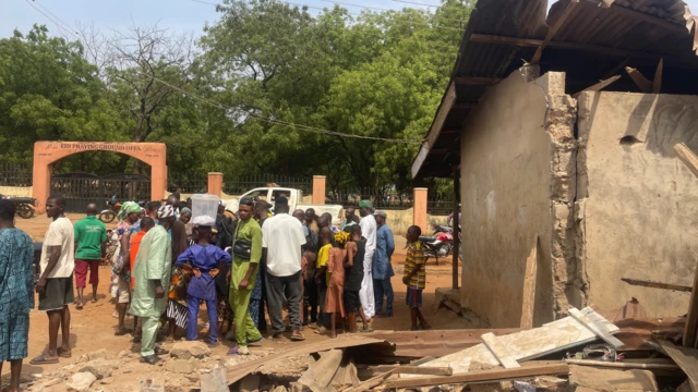 People gathered beside a damaged building