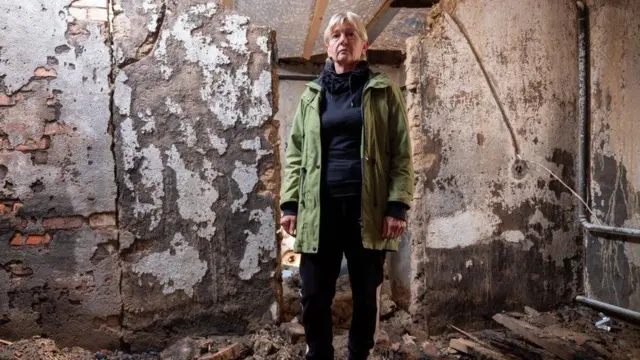 Liyubov Smirnova harabeye dönüşmüş evini gösteriyor