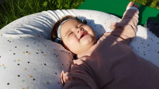 Laia allongée sur un oreiller au milieu de l'herbe.