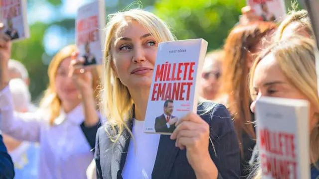 Dilek İmamoğlu bir çok kadının arasında, güneşli bir günde, eşi İmamoğlu hakkında yazılan "Millete Emanet" adlı kitabı elinde tutuyor.