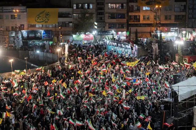 İran ve Hizbullah bayrakları taşıyan kalabalık bir kitle Tahran'da gösteri yapıyor.