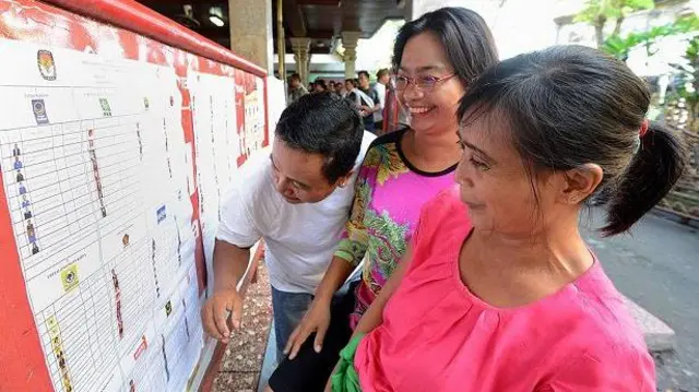 Warga melihat nama kandidat sebelum memberikan suara di tempat pemungutan suara selama pemilihan legislatif di Kuta, Bali.