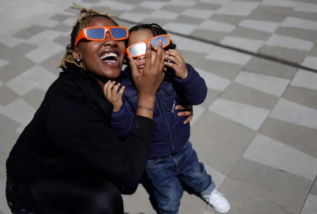 Mãe e filha observando o eclipse com óculoscasas de apostas com bonus gratisproteção 