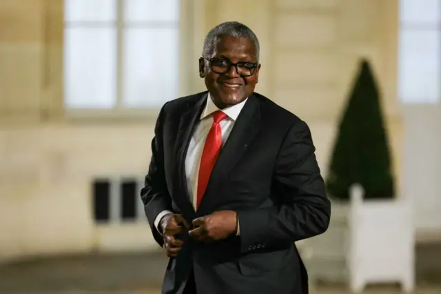 Aliko Dangote, en costume noir avec une chemise blanche et une cravate rouge