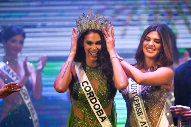 Magaly Benejam, on the left, from Córdoba, raises both hands to touch the crown on her head.