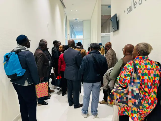 Abantu batonze umurongo imbere y'icumba kiberamo urubanza