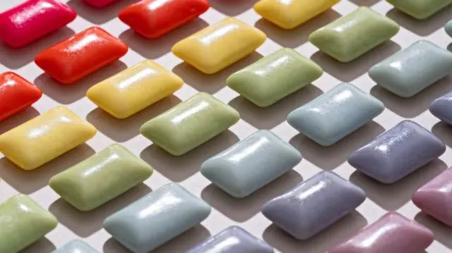 Yukarıdan aşağıya, kırmızı turuncu sarı yeşil mavi lila ve pembe renkli dikdörtgen sakızlar yanyana, sıralı  görünüyor, stok görseli. 