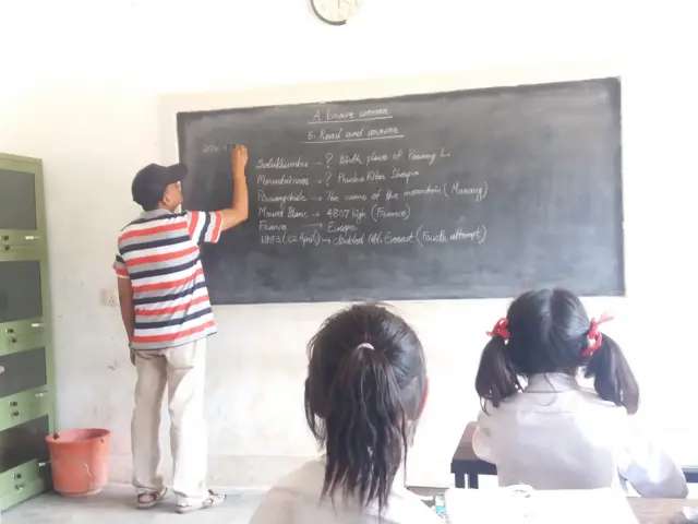 कक्षा कोठामा पढाउँदै एक शिक्षक