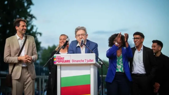 Меланшон на трибуне, на заднем плане довольные и аплодирующие люди