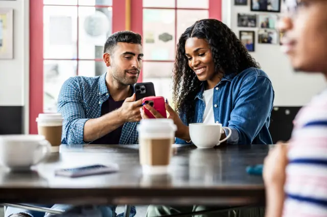 Un mexicano le muestra el teléfono a una chica negra.